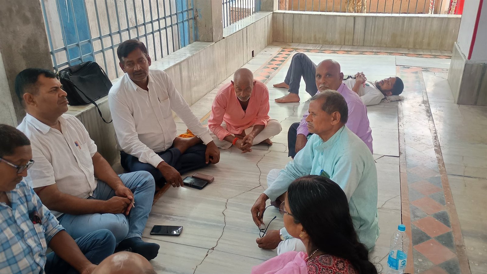 Samiti workers seated on the floor of a hall for a working meeting, June 2026.