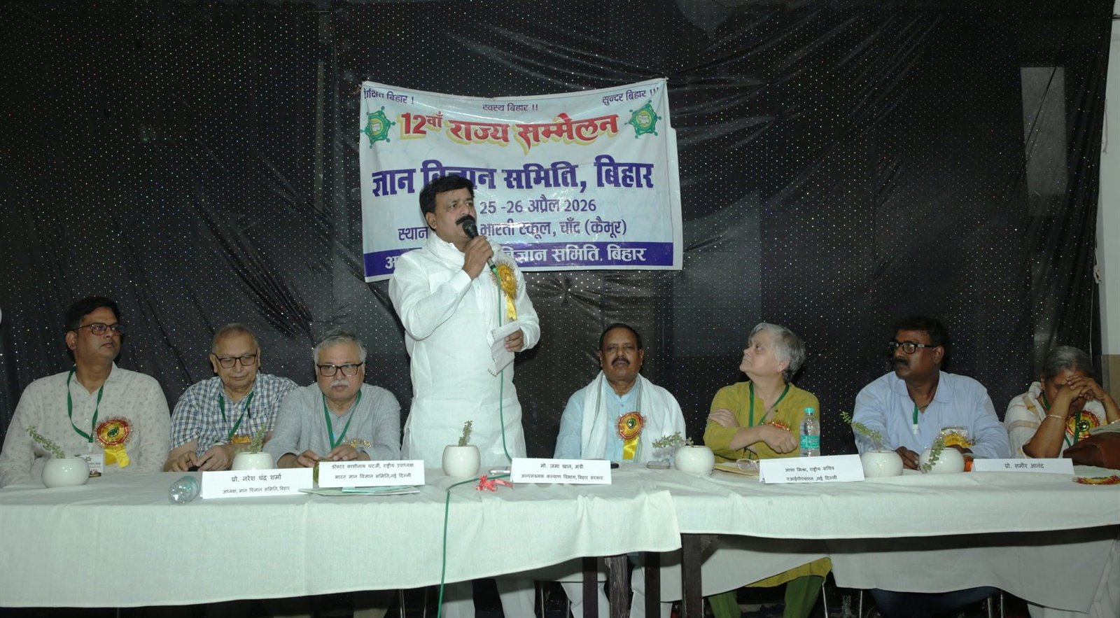 The dais of the 12th State Conference at Chand, Kaimur, April 2026, with Bihar's Minister for Minority Welfare Md. Jama Khan speaking at the microphone and the office bearers seated behind nameplates.
